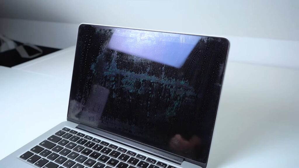 A MacBook Pro with a damaged display showing coating issues