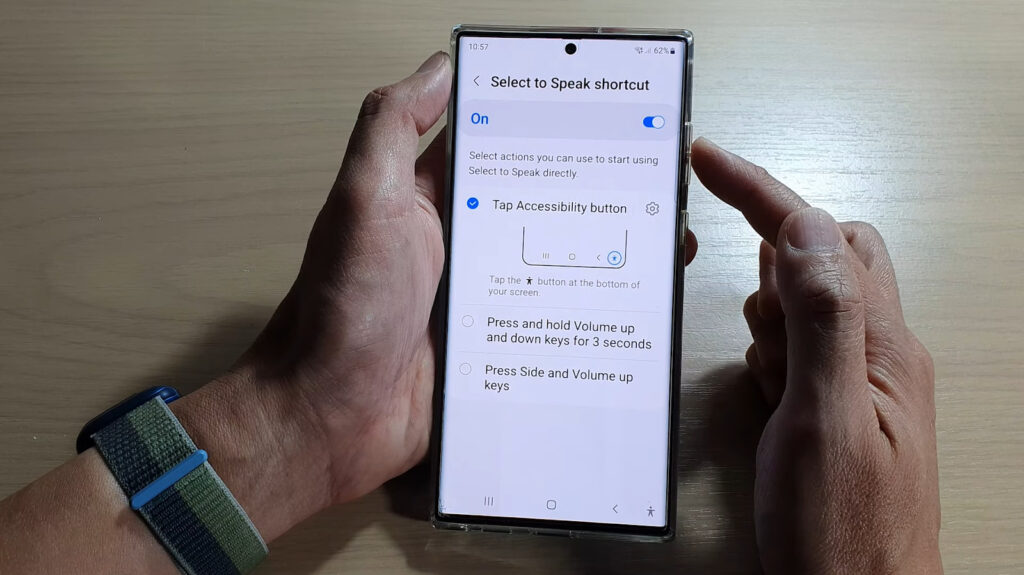 hand holding a smartphone with the "Select to Speak" shortcut settings on the display